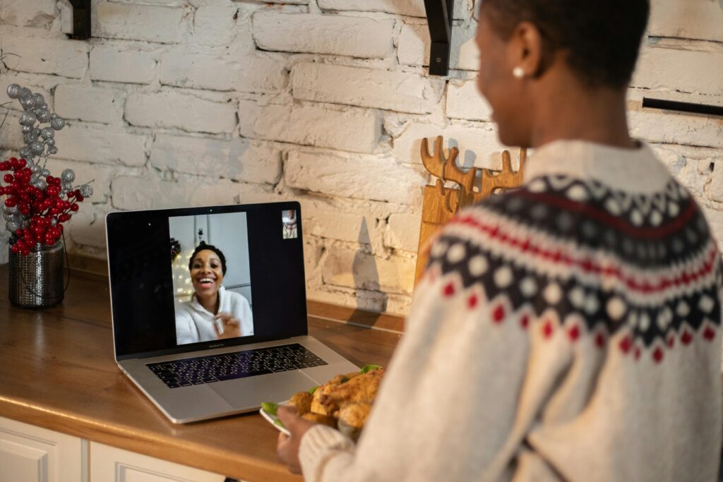 Two friends enjoy a video call during a cozy holiday gathering. Warm festive vibes.